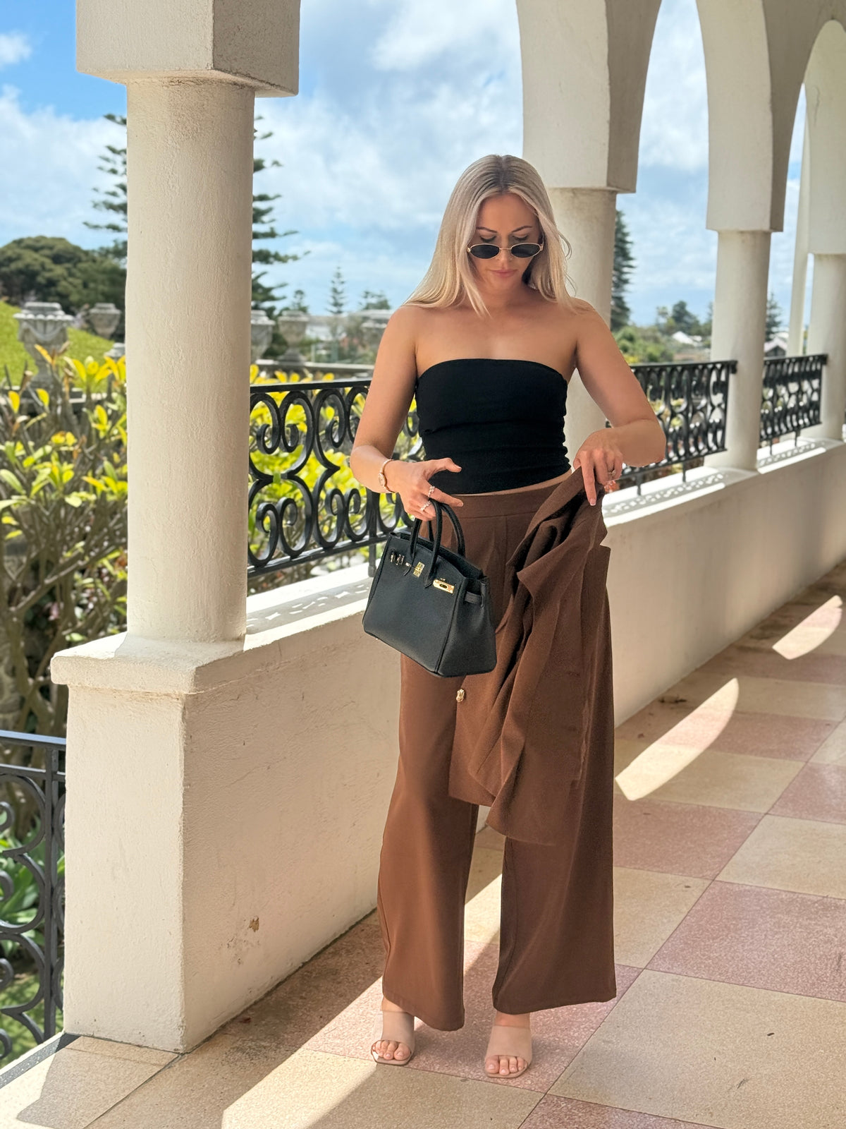 The Margaux wide leg trousers in chocolate, with the vest draped over the arm